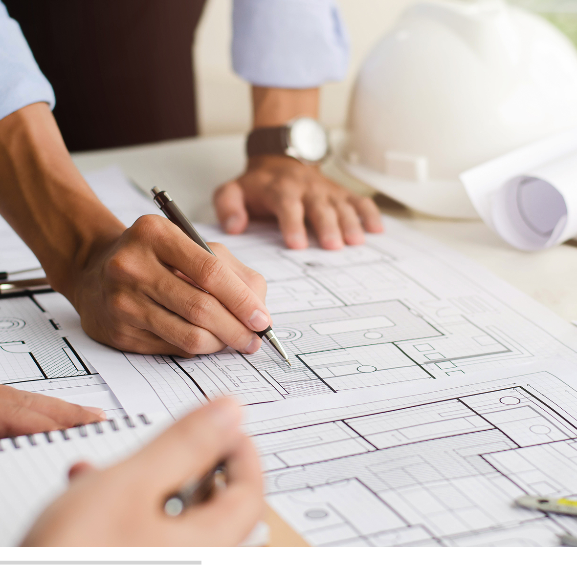 Hands working on architectural blueprints